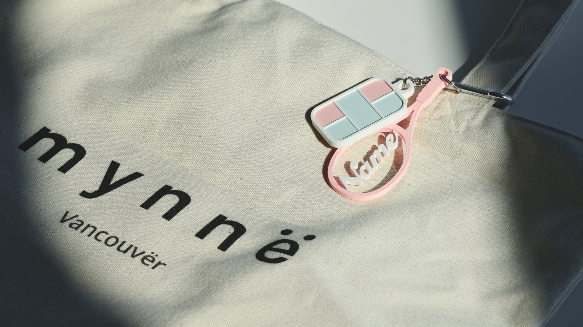 Pink personalized racquet and court charms on a Mynnë tote